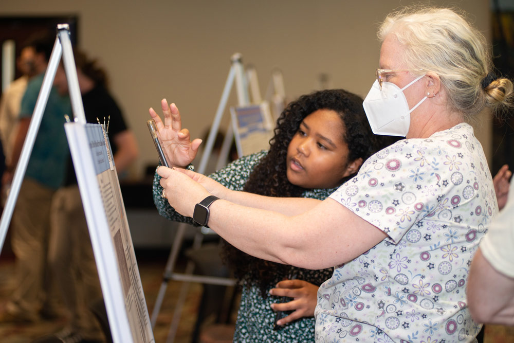 student discussing presentation board with person